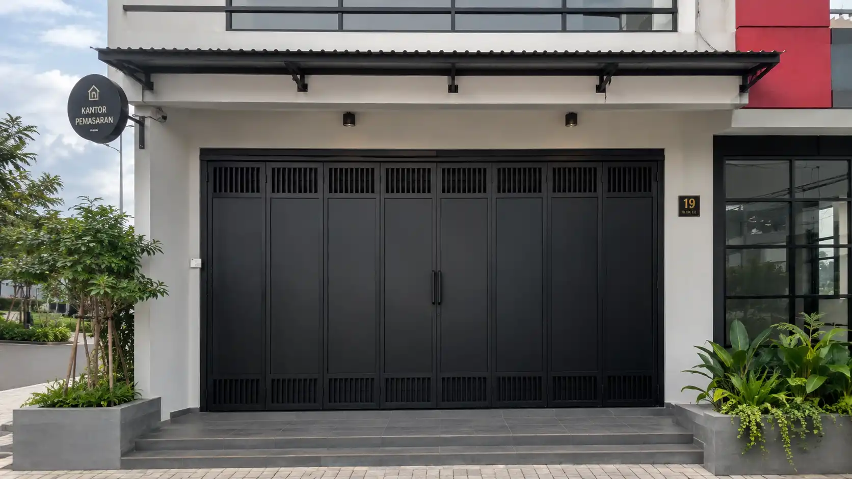 Pintu ruko besi minimalis berwarna hitam pada fasad toko modern yang bersih dan profesional.